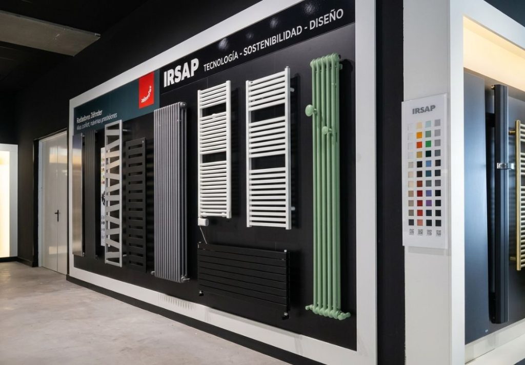 Showroom wall displaying a variety of radiators and heating panels under a black backdrop with IRSAP branding and a color sample card nearby.